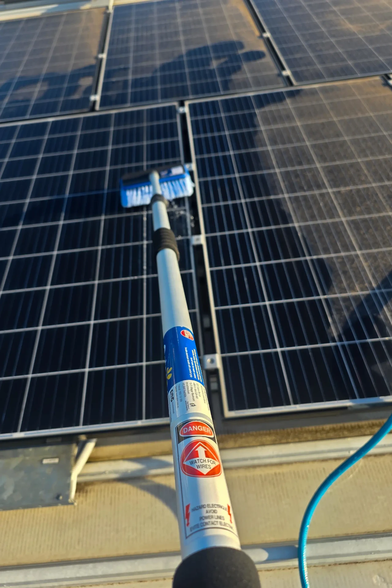 Commercial solar panel array being cleaned with a water fed pole, showing proactive property maintenance