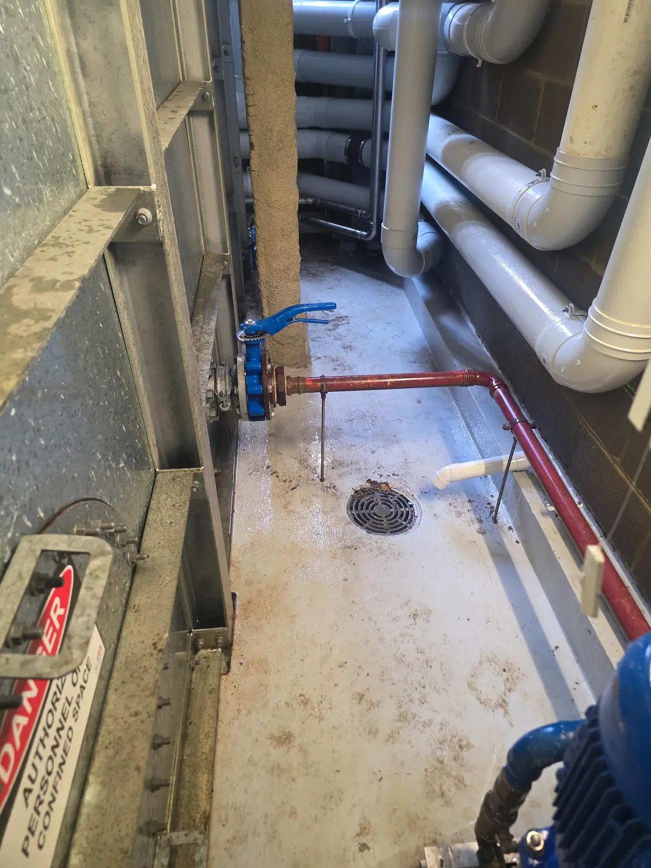 Valve and pipework repairs in a commercial plant room with floor drainage